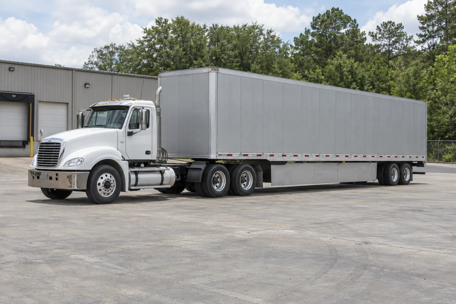 A white daycab tractor coupled to a plain silver freight trailer